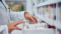 A pharmacist inspects a drawer of medicines.
